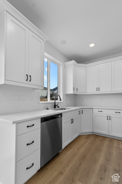 Kitchen featuring dishwasher, light countertops, light wood-type flooring, white cabinetry, and recessed lighting