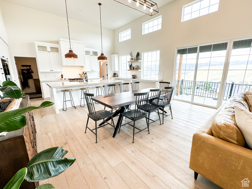 Dining area featuring a towering ceiling, light wood finished floors, and plenty of natural light