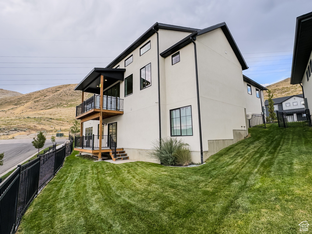 Rear view of property featuring a balcony, a fenced backyard, stucco siding, and a mountain view