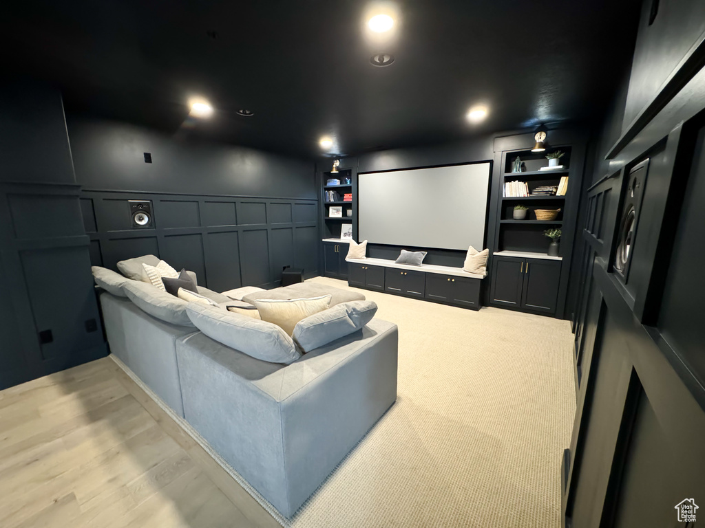 Home theater featuring a decorative wall, built in features, and a wainscoted wall
