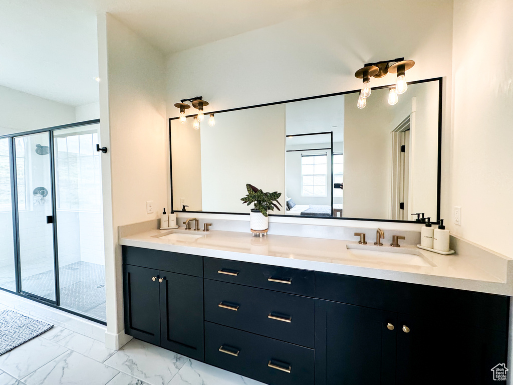 Bathroom with double vanity, a stall shower, and marble finish flooring