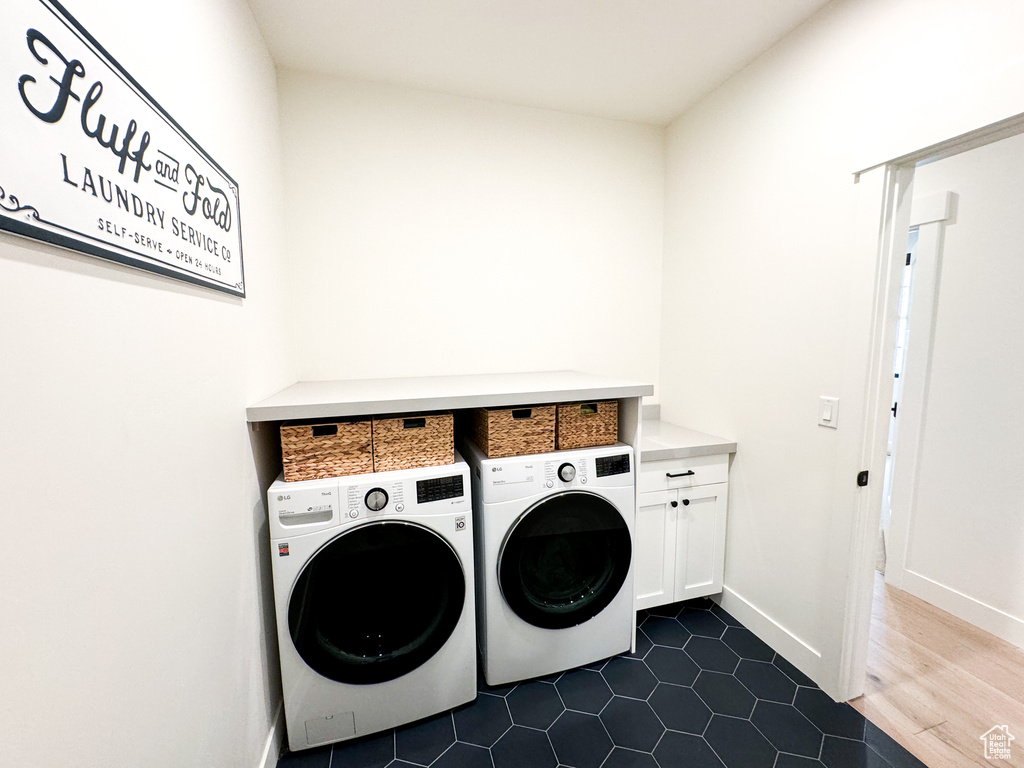 Washroom featuring cabinet space, washing machine and dryer, and dark tile patterned floors