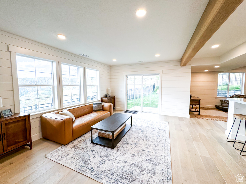 Living area featuring light wood-style floors, wooden walls, recessed lighting, and beamed ceiling