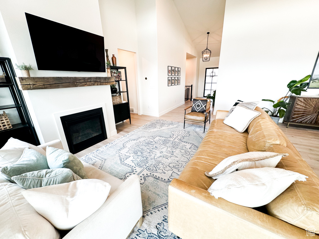 Living area featuring high vaulted ceiling, a fireplace, and light wood-style flooring