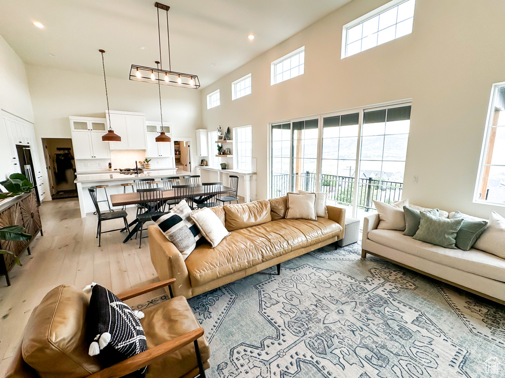 Living area with a high ceiling, light wood-type flooring, and recessed lighting