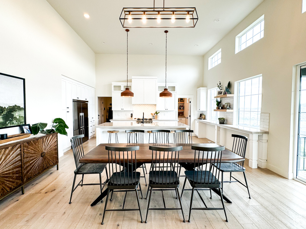Dining space with a towering ceiling, light wood-style flooring, and recessed lighting