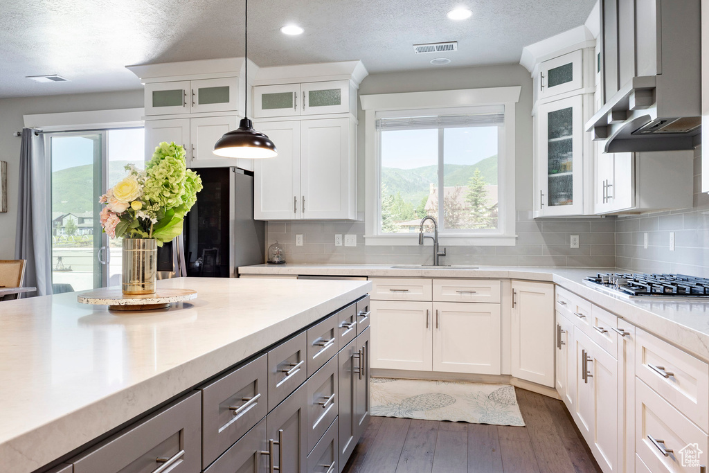 Kitchen with stainless steel gas cooktop, light countertops, gray cabinets, white cabinets, and recessed lighting