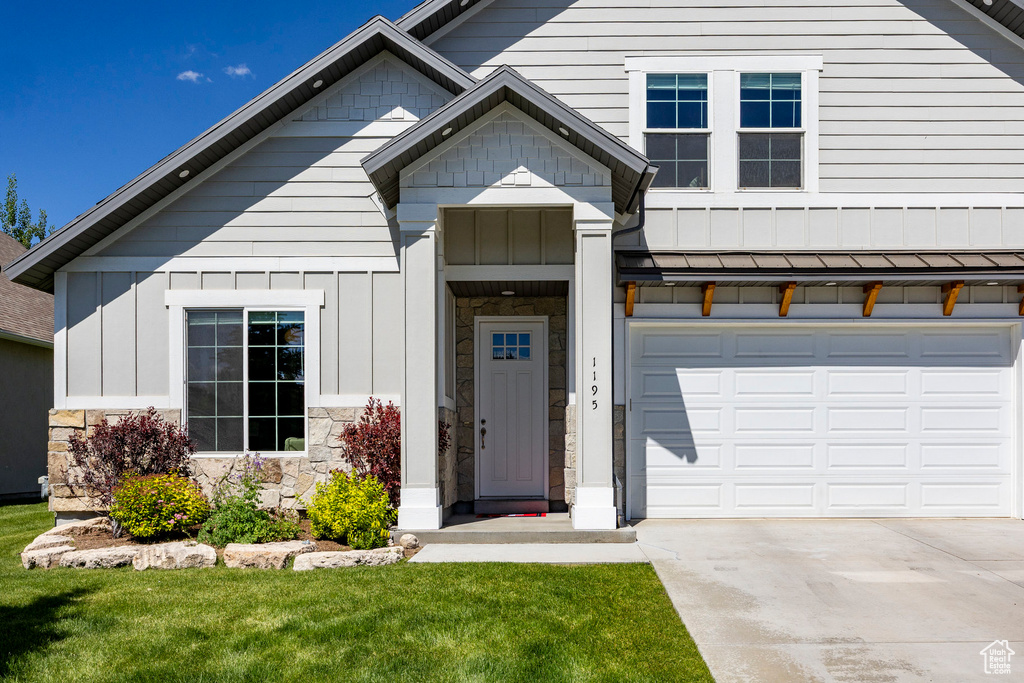 View of front of property with driveway, an attached garage, board and batten siding, and stone siding