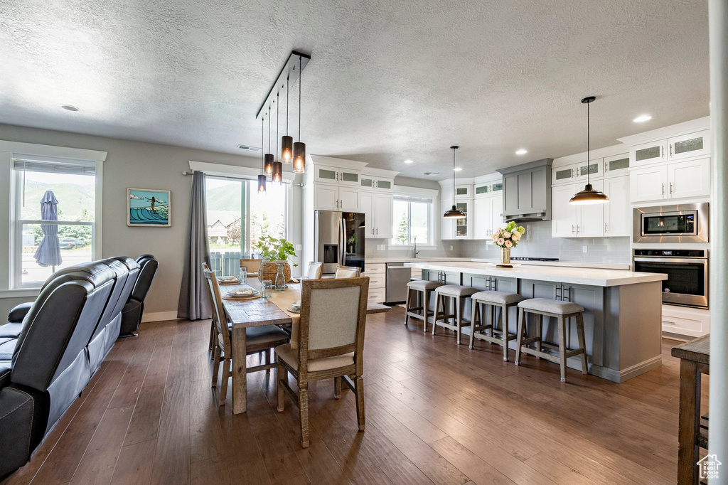 Dining area with a textured ceiling, dark wood-type flooring, and recessed lighting