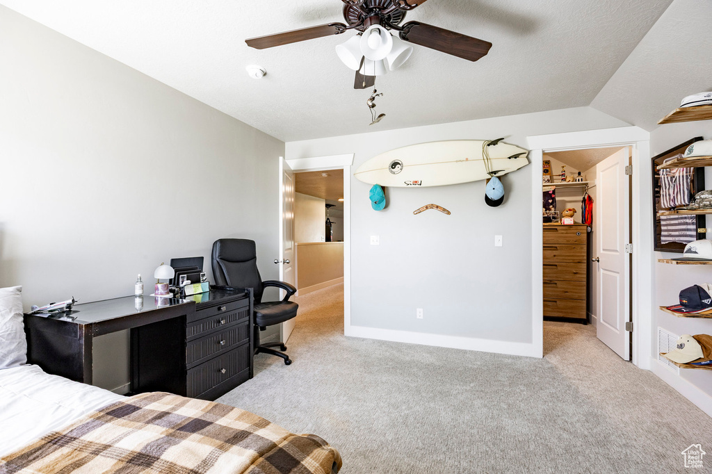 Bedroom with carpet flooring, a walk in closet, an office area, a ceiling fan, and a closet