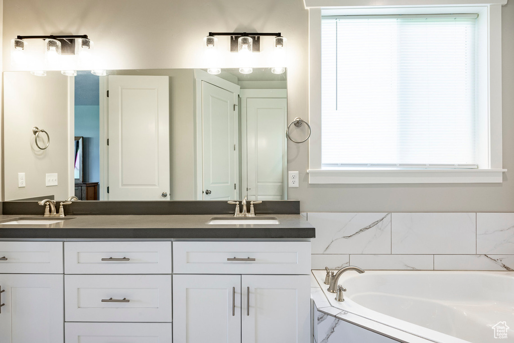 Full bath featuring double vanity, plenty of natural light, and a garden tub