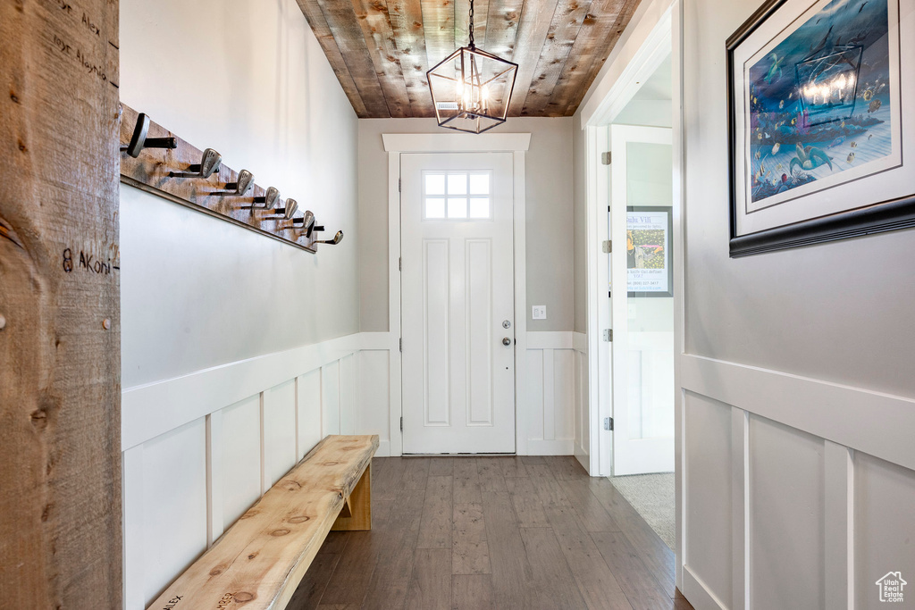 Entryway with wood ceiling, a chandelier, hardwood / wood-style floors, a wainscoted wall, and a decorative wall