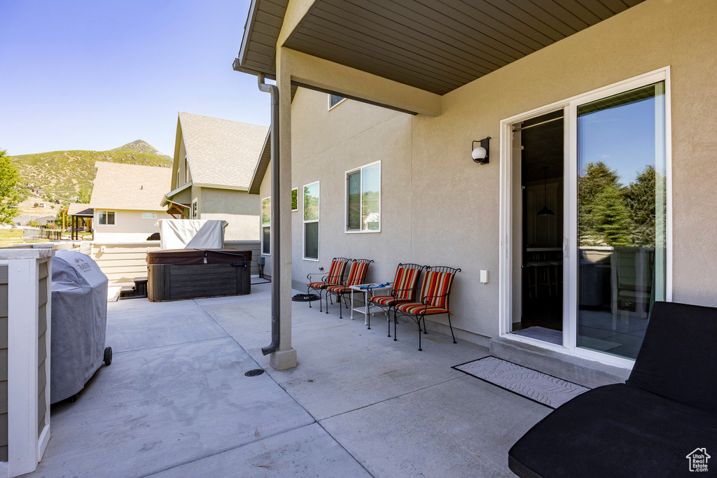 View of patio featuring a hot tub, a mountain view, and grilling area