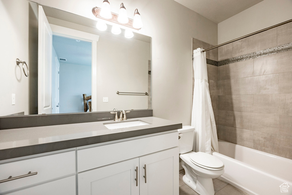Full bath featuring vanity, shower / bath combo with shower curtain, and tile patterned floors