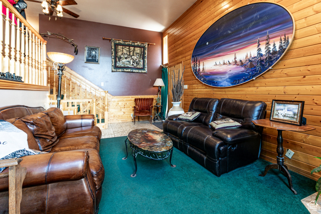 Carpeted living room featuring wooden walls and a ceiling fan