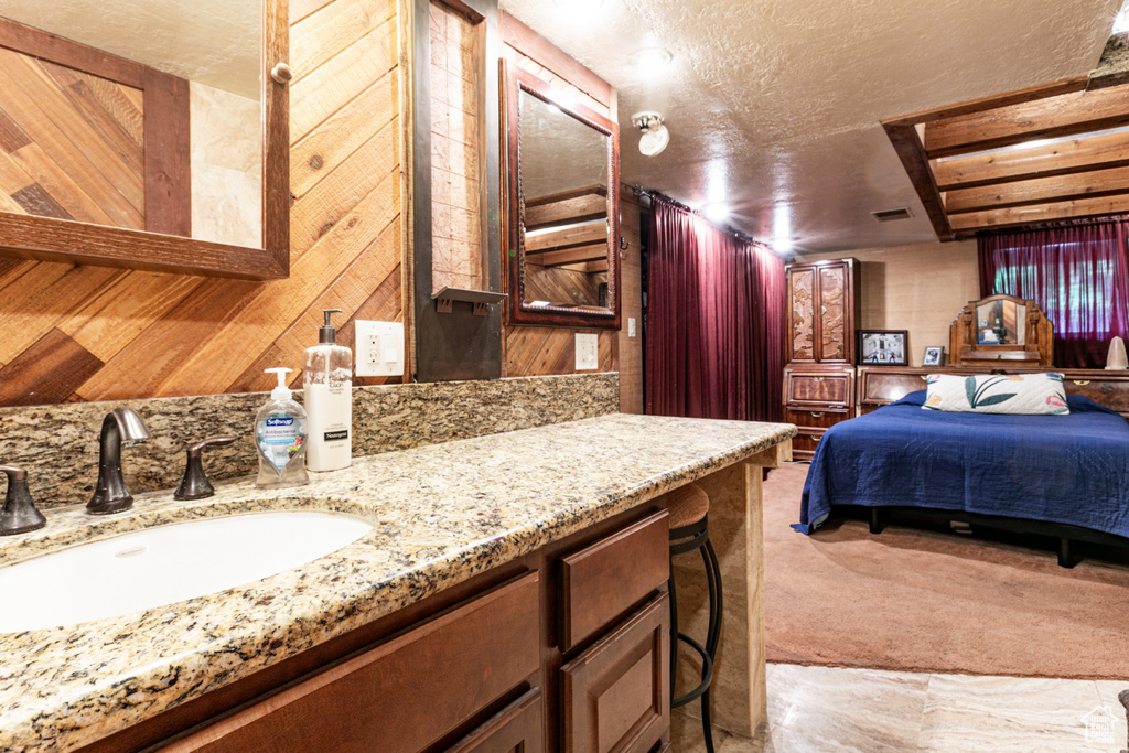 Bedroom featuring a textured ceiling, light carpet, and wood walls