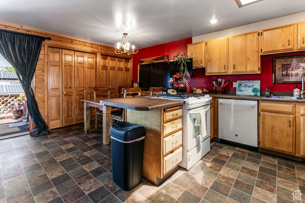 Kitchen with white appliances, a peninsula, stone finish flooring, dark countertops, and recessed lighting