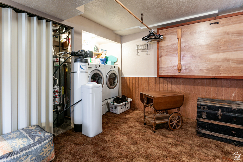 Laundry room with carpet, a textured ceiling, independent washer and dryer, wainscoting, and wood walls