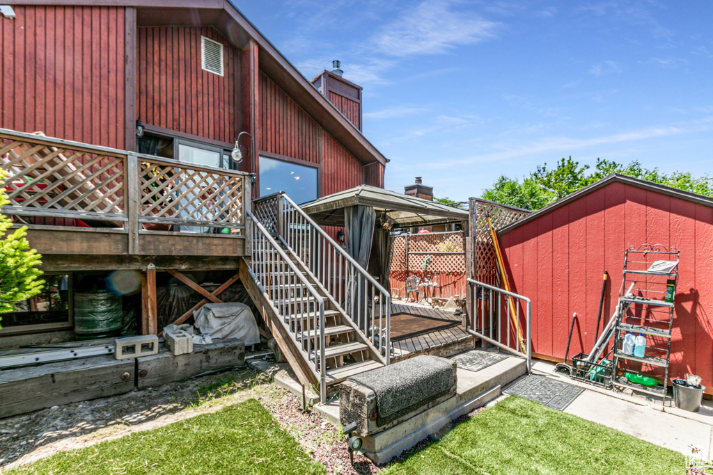 Rear view of house featuring stairway, a chimney, a shed, and a wooden deck