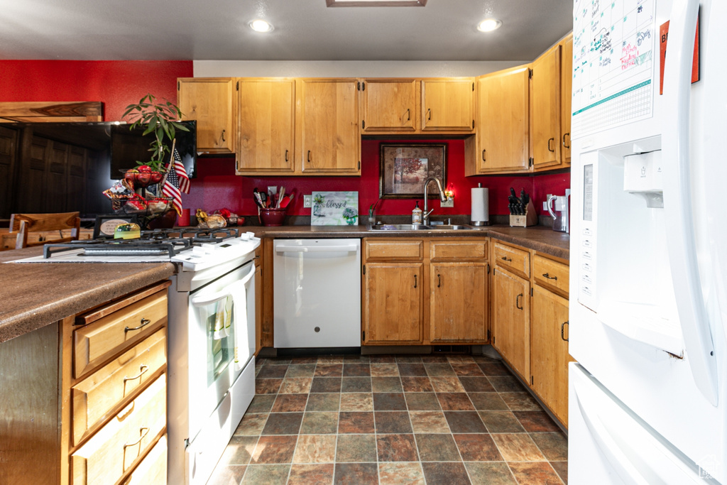 Kitchen featuring white appliances, stone finish floors, dark countertops, and recessed lighting