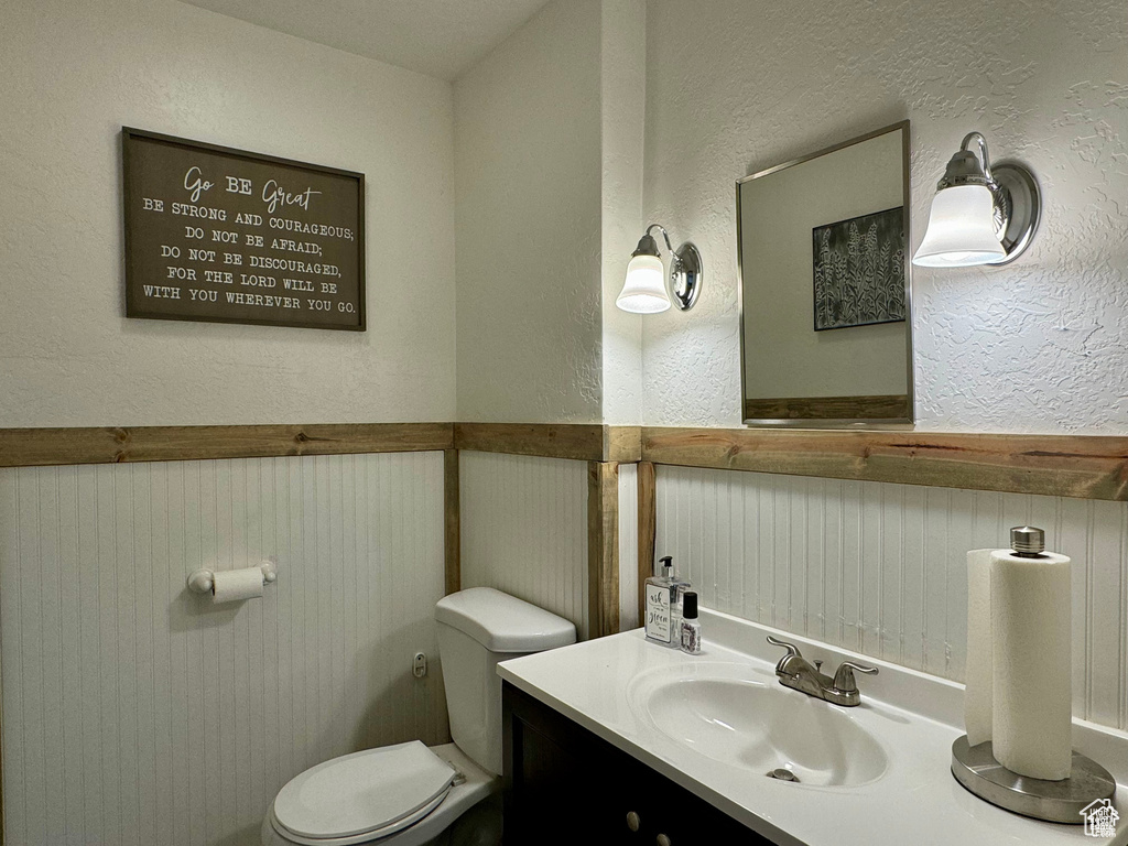 Bathroom featuring a wainscoted wall, a textured wall, and vanity