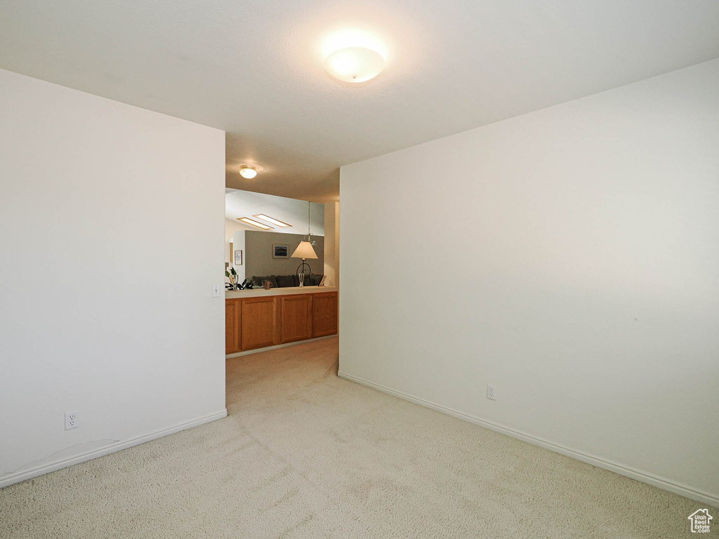 Empty room featuring light colored carpet and baseboards