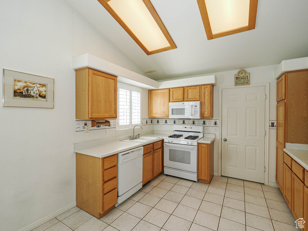 Kitchen featuring white appliances, lofted ceiling, light countertops, and light tile patterned flooring
