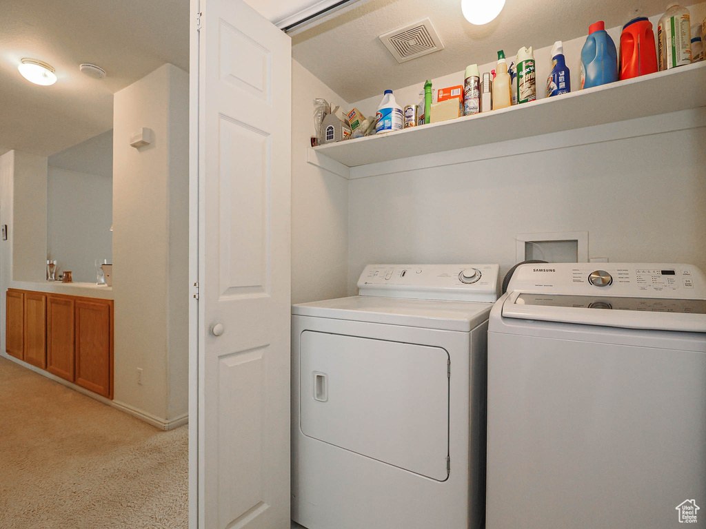 Laundry room featuring washing machine and dryer and light colored carpet