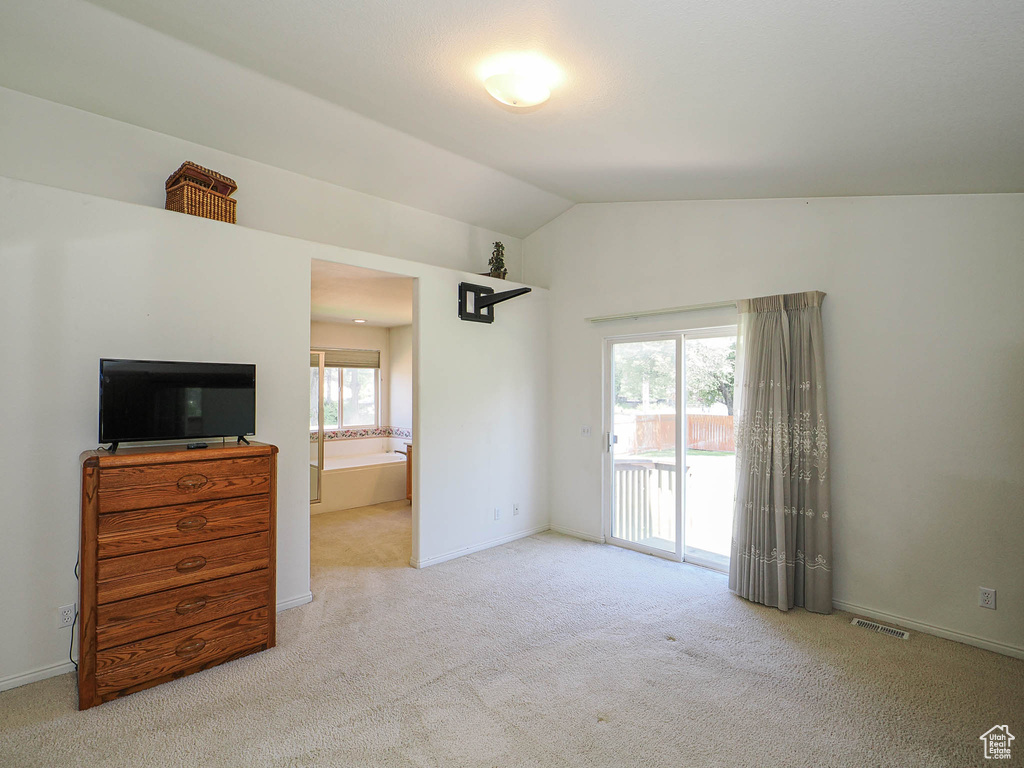 Bedroom with access to outside, carpet floors, vaulted ceiling, and ensuite bathroom
