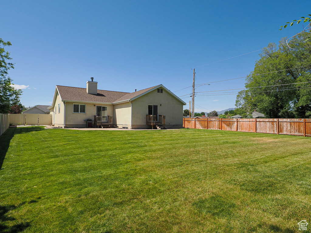 Back of property featuring a fenced backyard, a chimney, a patio, and stucco siding