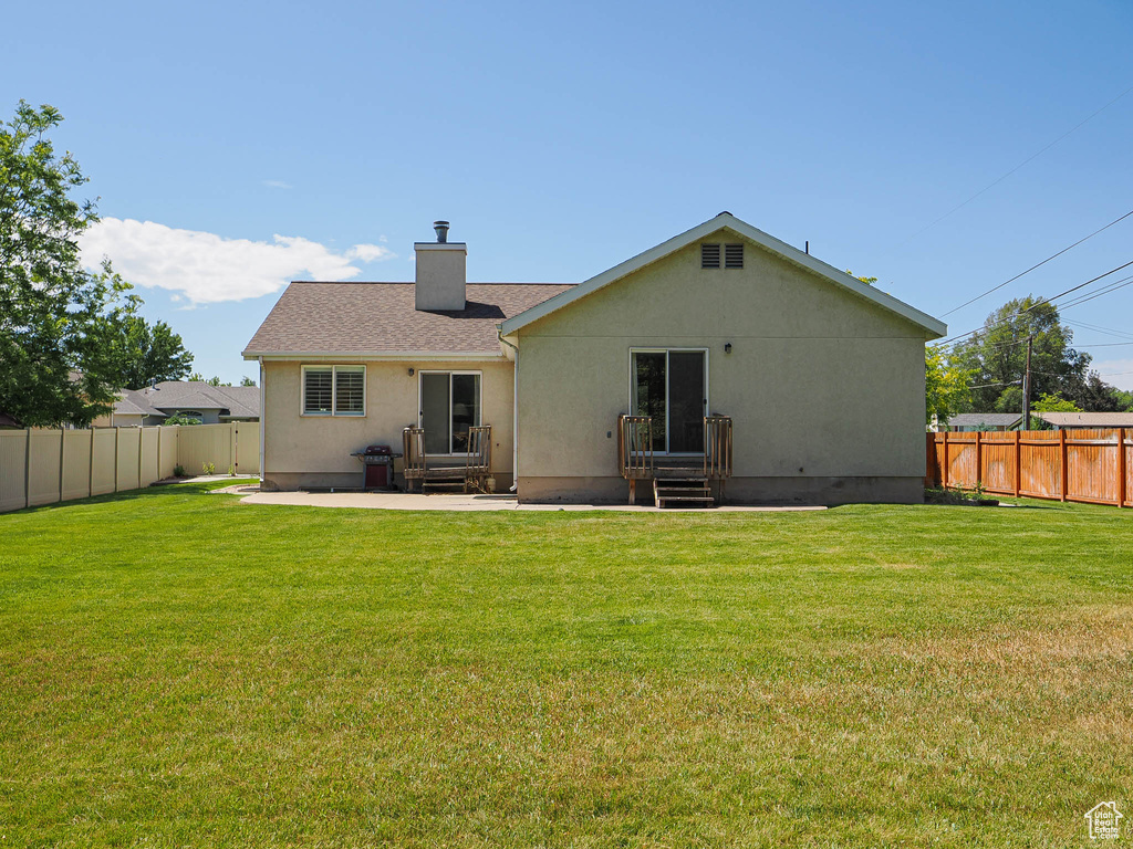 Back of house featuring a chimney, a fenced backyard, a patio area, stucco siding, and entry steps