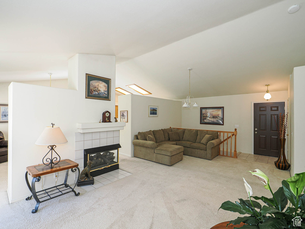 Living area with vaulted ceiling, carpet, and a tiled fireplace