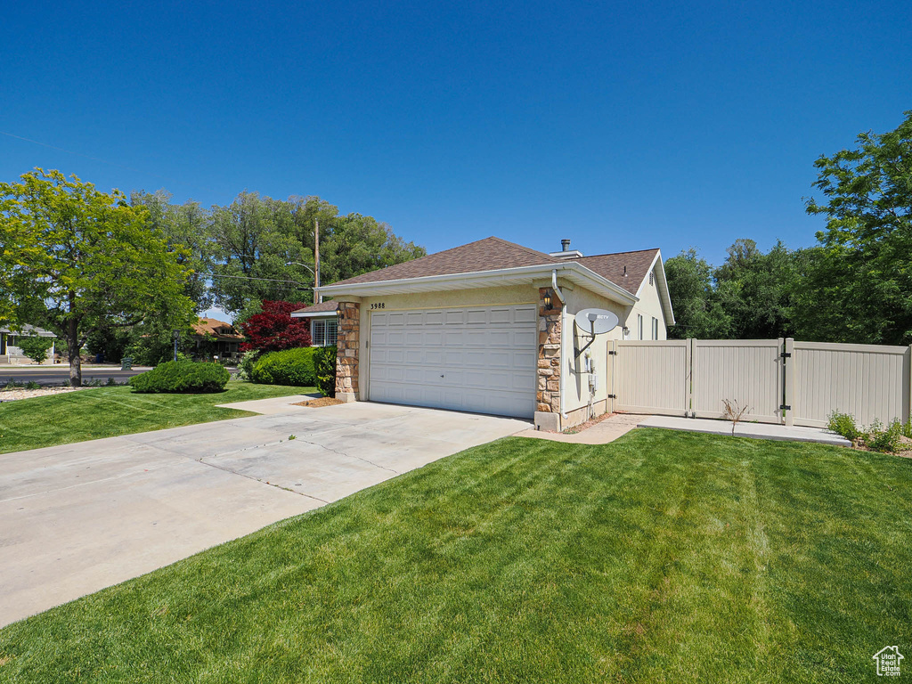 View of side of property with a gate, roof with shingles, stone siding, driveway, and a garage