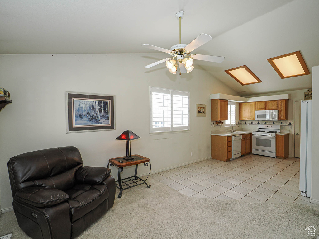 Kitchen with white appliances, light countertops, open floor plan, vaulted ceiling, and light tile patterned floors