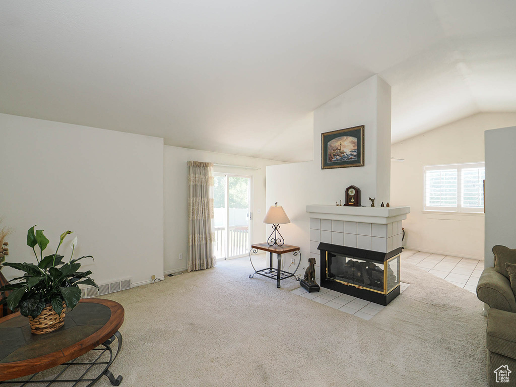 Carpeted living room with lofted ceiling and a fireplace
