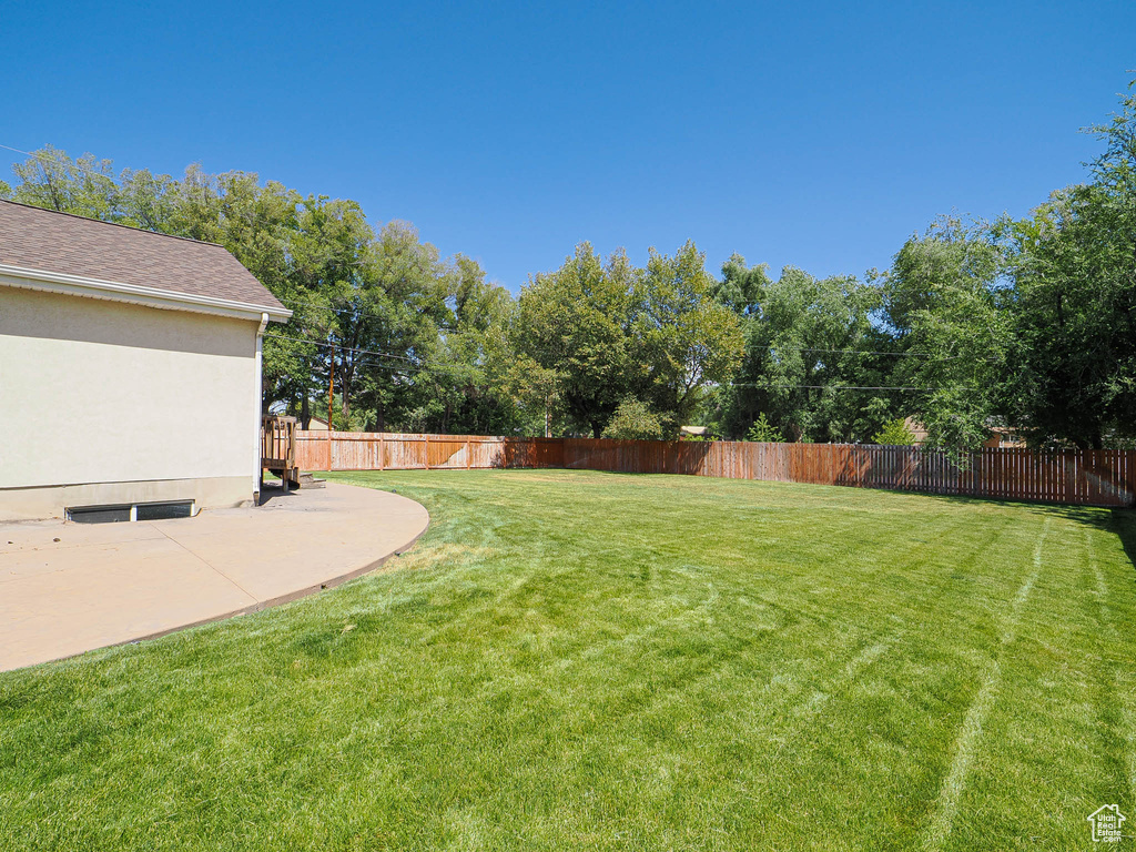 Fenced backyard with a patio and view of scattered trees