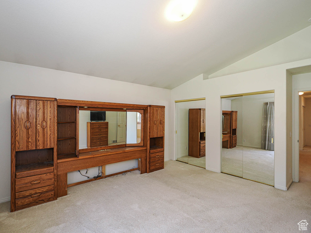 Unfurnished bedroom with carpet, lofted ceiling, and two closets