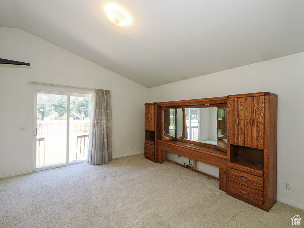 Unfurnished living room featuring vaulted ceiling, carpet, and healthy amount of natural light
