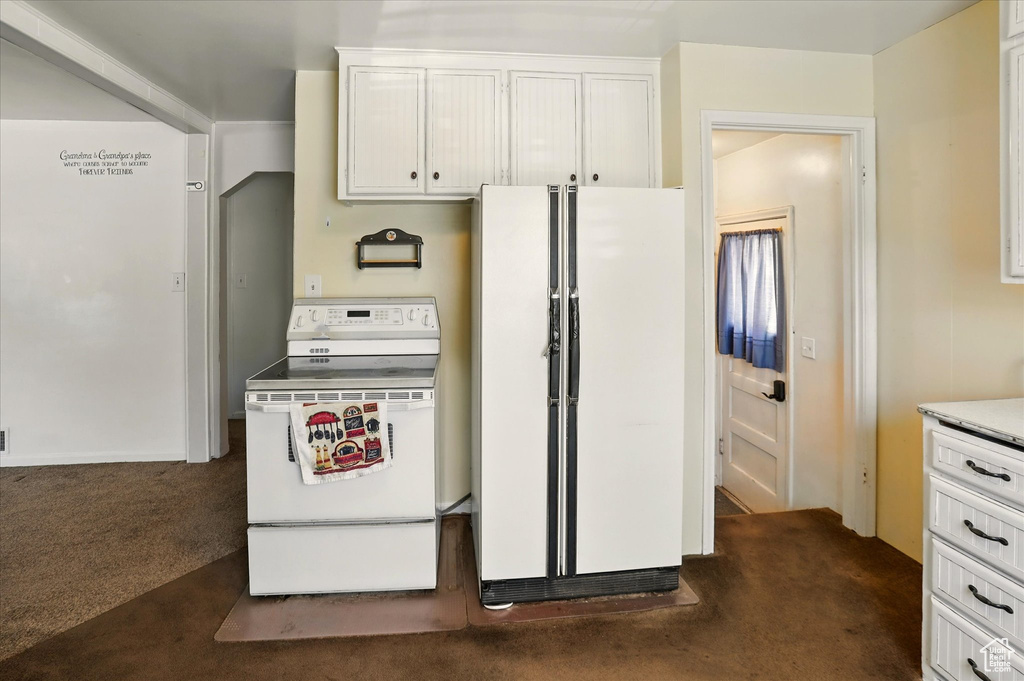 Kitchen featuring white appliances, dark colored carpet, white cabinets, and light countertops