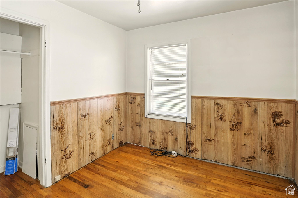 Unfurnished room featuring a wainscoted wall, wood finished floors, and wood walls