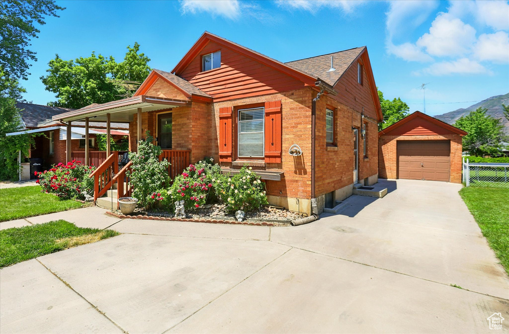 View of front of property with an outdoor structure, a porch, a mountain view, a garage, and driveway