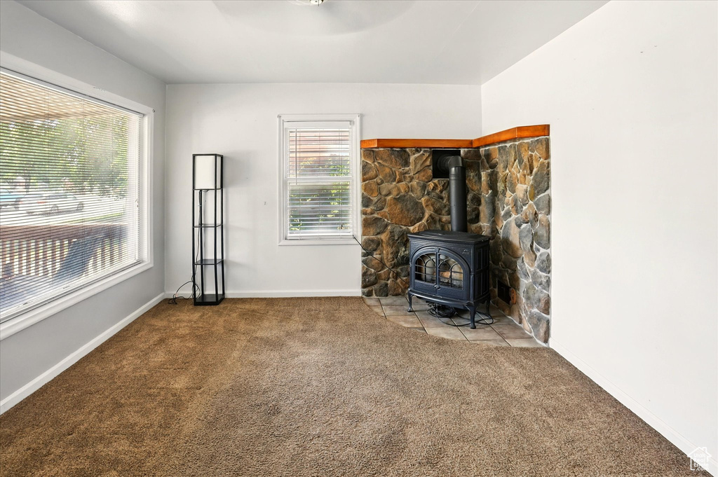 Carpeted living area with a wood stove, baseboards, and a ceiling fan