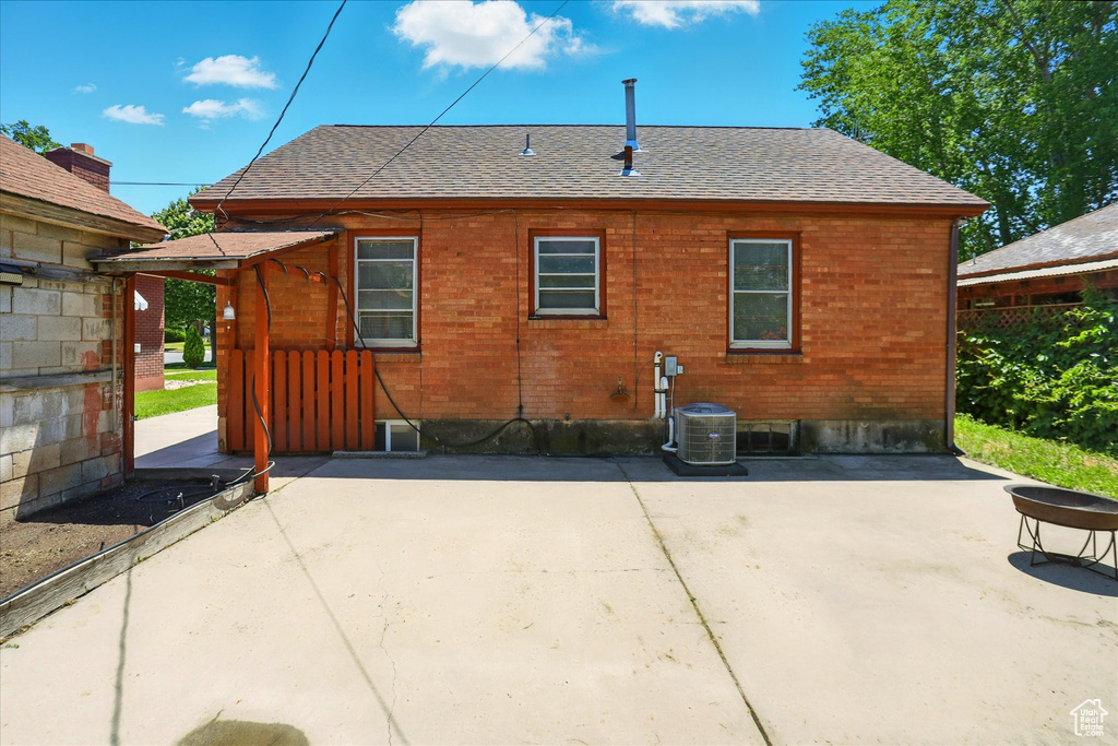 Rear view of house featuring a patio area, roof with shingles, and cooling unit