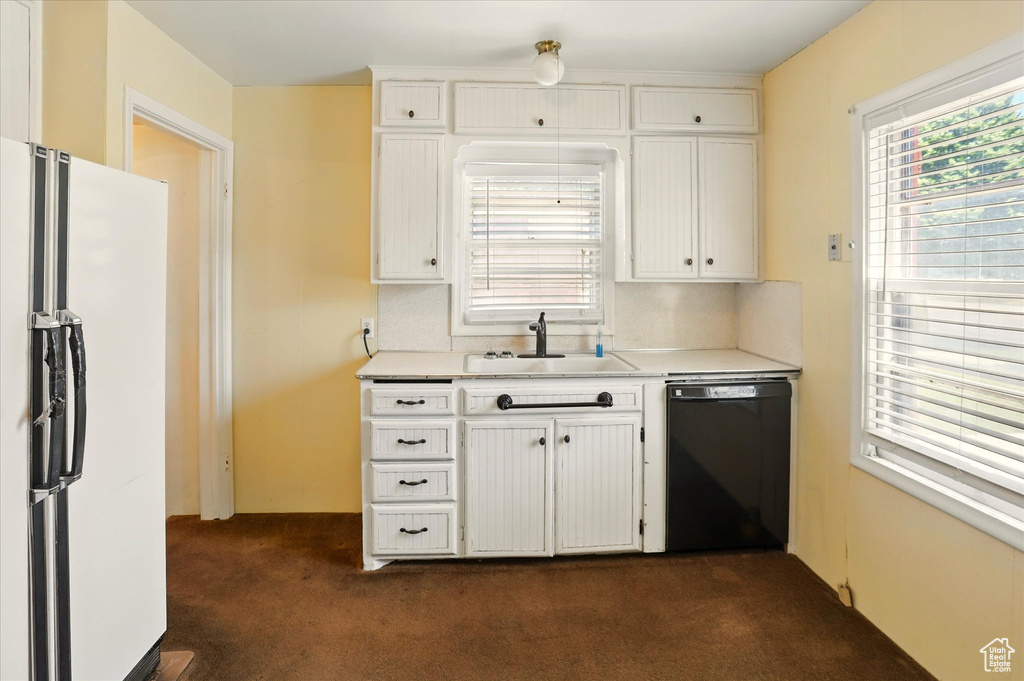 Kitchen with dishwasher, freestanding refrigerator, a sink, dark colored carpet, and light countertops