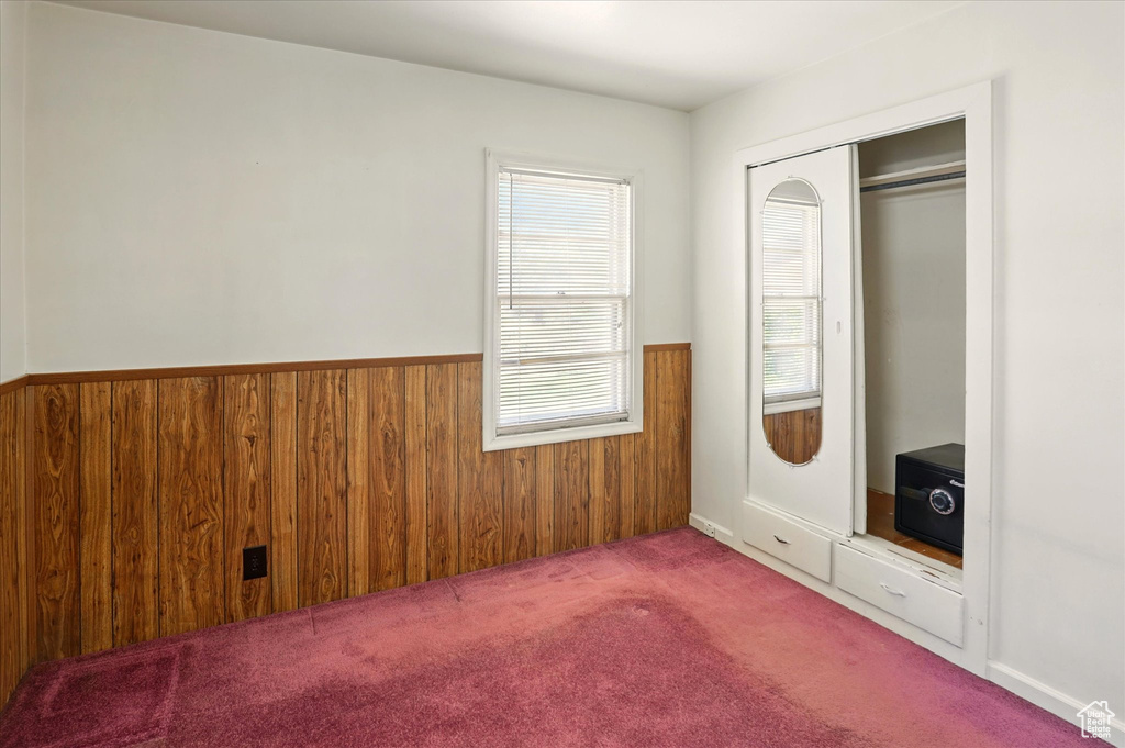 Unfurnished bedroom featuring wainscoting, carpet floors, wood walls, and a closet