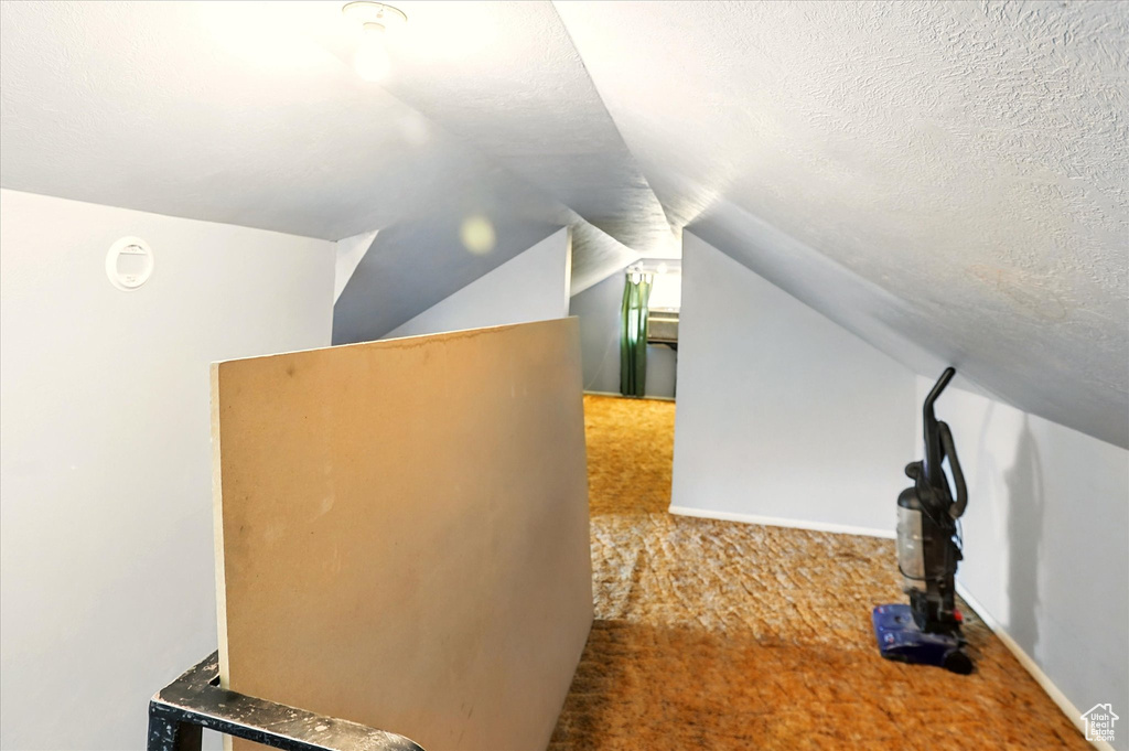 Bonus room featuring lofted ceiling, carpet floors, and a textured ceiling