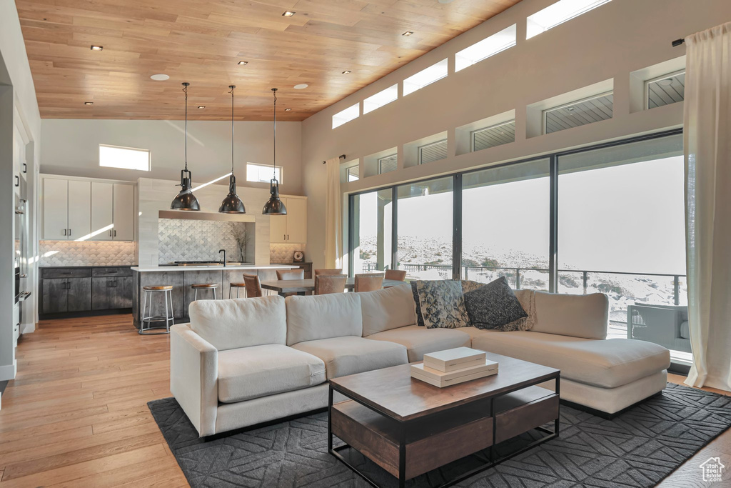 Living area with wood ceiling, a high ceiling, light wood finished floors, and recessed lighting