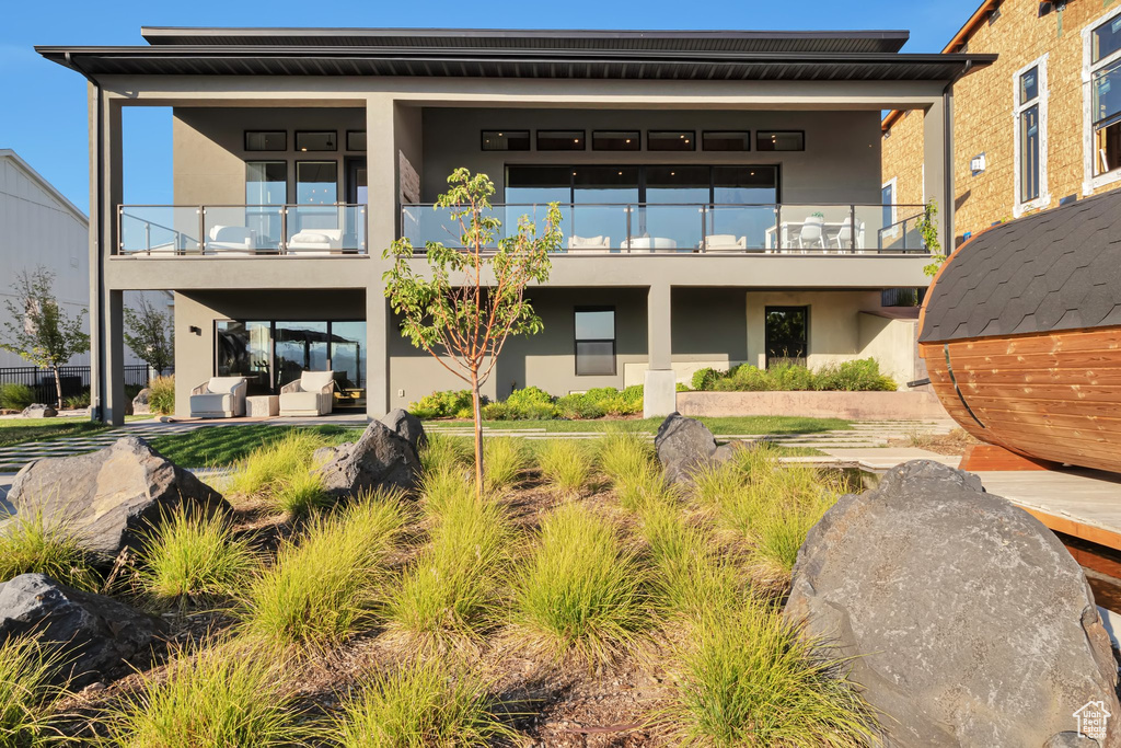 Rear view of house featuring a balcony and stucco siding