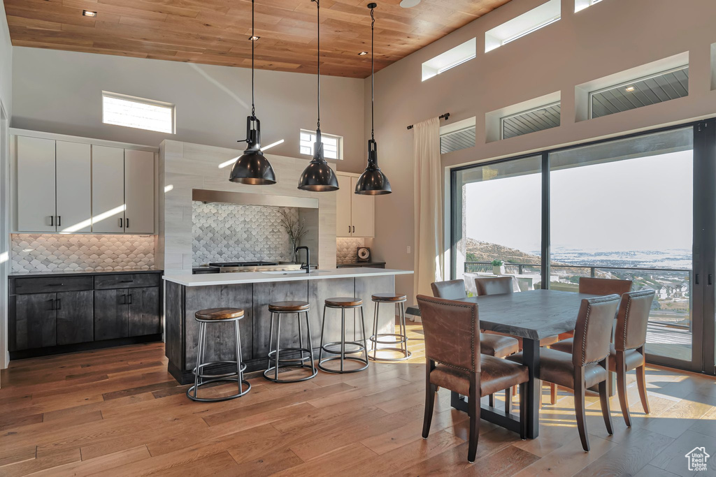 Dining room featuring high vaulted ceiling, wood ceiling, plenty of natural light, and light wood-style floors