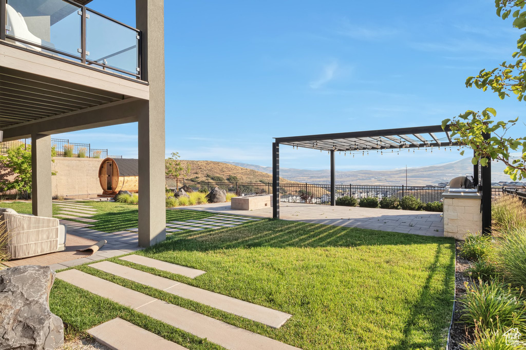 View of yard featuring a mountain view, a patio, a pergola, and a balcony